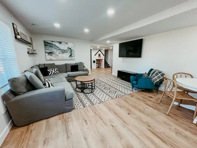 Finished basement family room in the Kansas City area with gray sectional, wood-look plank floor and recessed lights
