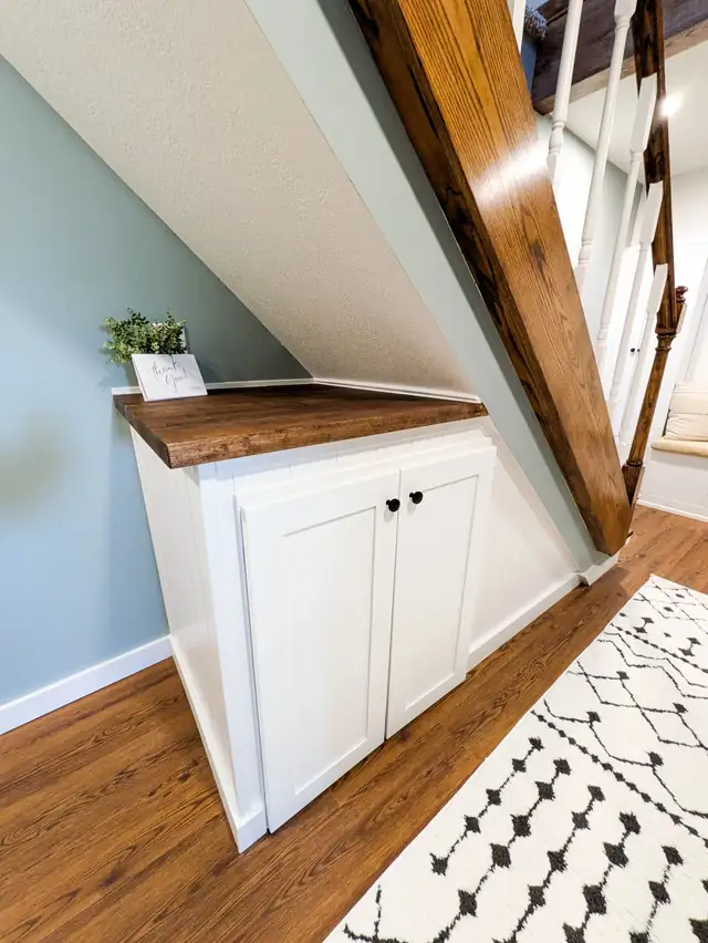 Grain Valley, MO basement finish with a wood-topped white cabinet tucked under the stairs