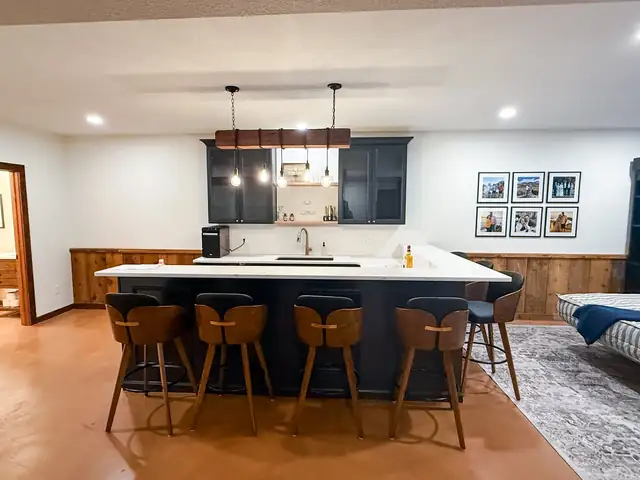 Black basement kitchenette bar with box trim, pendant lights and leather stools in a Grain Valley, Missouri basement remodel