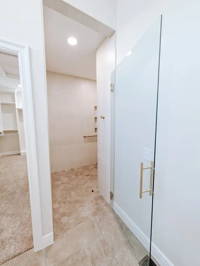 Walk-in shower with custom glass door and gold accents in a Lee's Summit bathroom remodel
