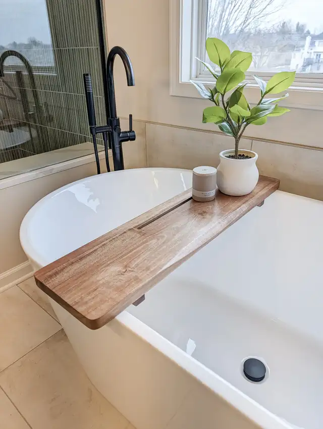 Freestanding tub with black floor-mounted faucet and wood bath tray in a Lee's Summit spa bathroom