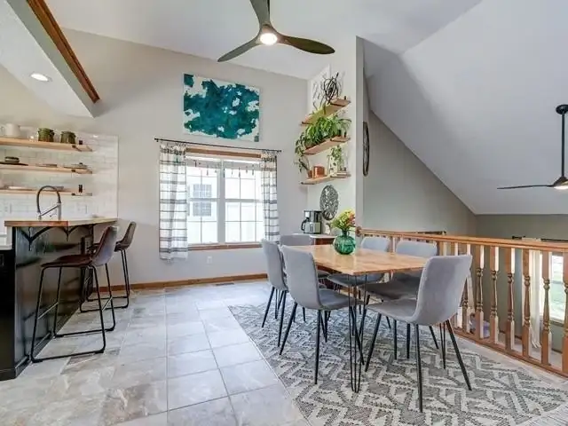 Open kitchen and dining area in Lee's Summit with floating wood shelves, bar seating and patterned tile floor