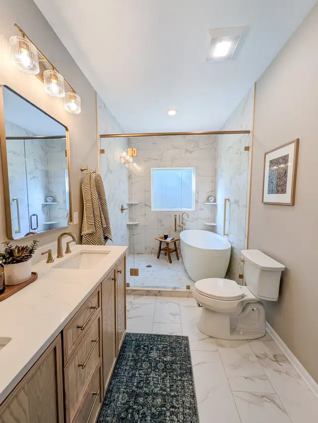 Olathe bathroom remodel by Haven Reno KC with a freestanding tub inside a frameless glass shower, marble-look tile and brass fixtures